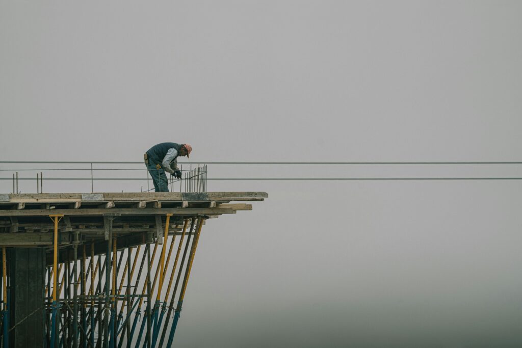 Worker on construction site framework against a cloudy sky in Denizli, Türkiye.